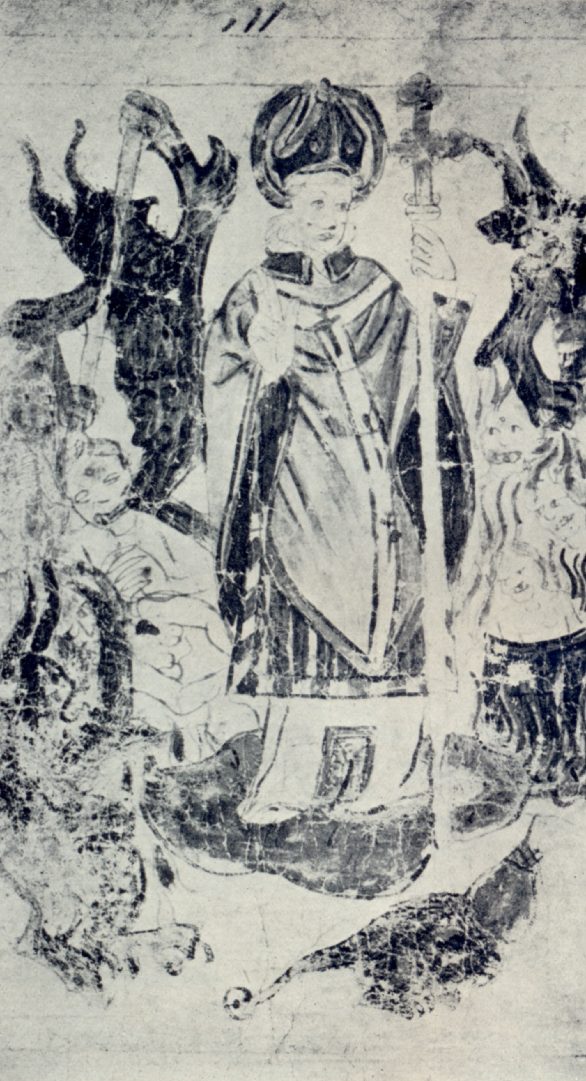 A manuscript illustration in pen and coloured wash: a tonsured figure stands within a rocky opening while several small dark figures with clawed limbs press around him; a landscape and building appear above.